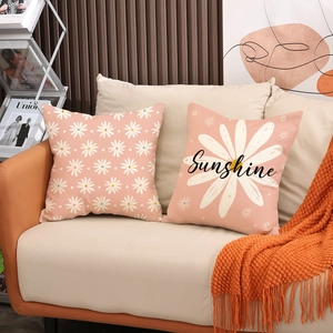 Detail of two pink daisy linen pillowcases with Sunshine script on a cozy sofa