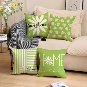 Detail of four green daisy linen pillow covers with floral patterns and artistic typography