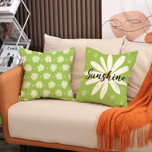 Detail of green linen pillow covers with white daisy print and Sunshine text on a sofa