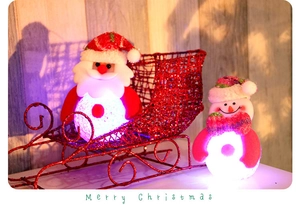 Close-up of glowing LED Santa and snowman figures in a red glittery sleigh basket
