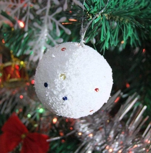 Close-up of 4cm white Christmas snowballs with colorful sequins hanging on a festive tree