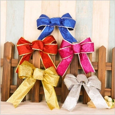 Glitter fabric Christmas bows in five colors hanging on a wooden fence for decoration