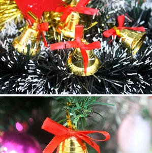 Detail of golden Christmas bells with red ribbon bows hanging on pine tree branches