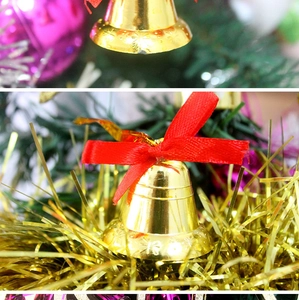 Close-up of golden Christmas bells with red bows and snowflake pattern on tree