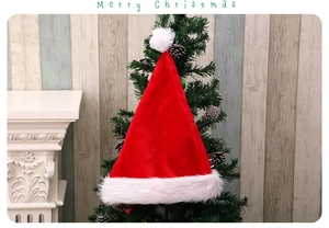 Classic red plush Santa hat with thick white fur trim on a decorated Christmas tree top