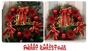 Close-up of Christmas wreath with red ornaments, bows and Merry Christmas gold signage