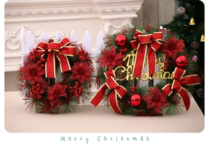 Detail of Christmas wreath set with red flowers, gold Merry Christmas sign and bows