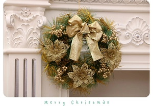 Detailed Christmas wreath with golden poinsettias, bows and berries on white fireplace