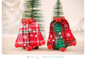 Detail view of plaid fabric Christmas bell ornaments with snowflakes and red pom-poms