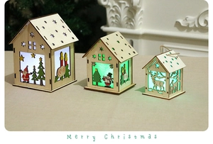 Close-up of three glowing wooden Christmas house ornaments with festive laser-cut patterns