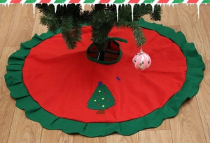 Detail of red Christmas tree skirt with green ruffled edges and embroidered tree decor