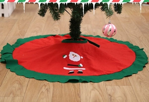 Close-up of red non-woven Christmas tree skirt with green scalloped edges and Santa Claus motif