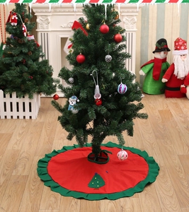 Detail of red Christmas tree skirt with green ruffled edges and tree embroidery