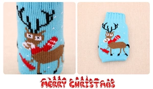 Detail of blue knitted Christmas beer bottle cover with reindeer and Merry Christmas text