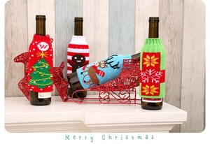 Detail of knitted Christmas wine bottle covers with reindeer and snowflake patterns