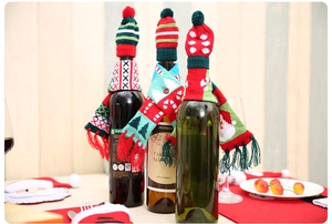 Detail of Christmas wine bottle decoration featuring mini knitted hats and striped scarves