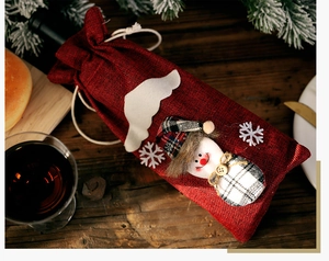 Close-up of a burlap Christmas wine bottle bag featuring a 3D snowman with plaid accessories