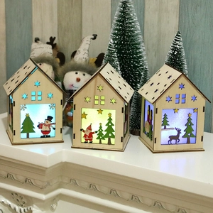 Trois maisons de Noël en bois DIY lumineuses avec LED sur un rebord de cheminée