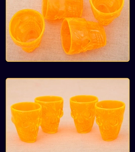 Detailed view of four orange translucent skull-shaped cups with gothic bone relief details