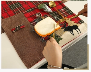 Makro-Detail des Weihnachts-Platzsets mit Karostoff, Rentier-Applikation und Sternbestickung