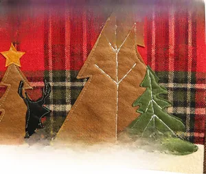 Macro view of Christmas plaid placemat with reindeer and tree appliqué embroidery