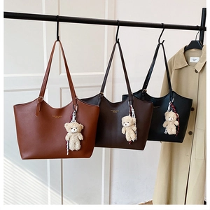Detailed view of leather tote bags in brown and black with bear charms and scarves