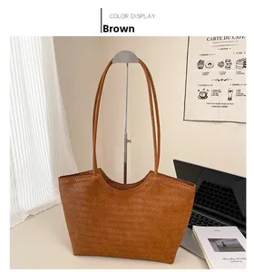 Detail of a brown woven tote bag featuring a high-quality herringbone weave and slim straps