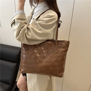 Grote bruine tote bag met strikpatronen in reliëf en dunne schouderbanden op model