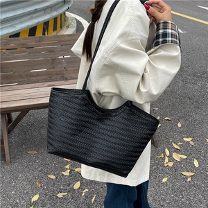 Minimalist black woven tote bag featuring large capacity and unique wavy top edge design