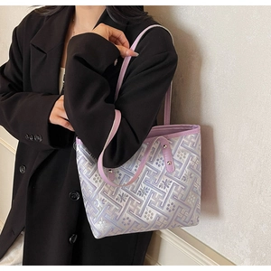 Ethnic tote bag with purple geometric patterns shown on shoulder with black suit