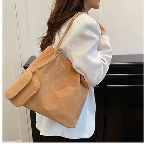 Detail view of large camel tote bag with side lettering and matching small zipper pouch