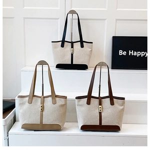 Close-up of three color-block canvas tote bags with leather trim and metal twist locks