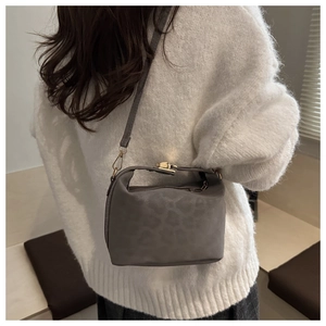 Detail view of a gray leopard print crossbody doctor bag with golden hardware on a model