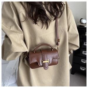 Brown vintage leather handbag with gold buckle shown on a trench coat outfit