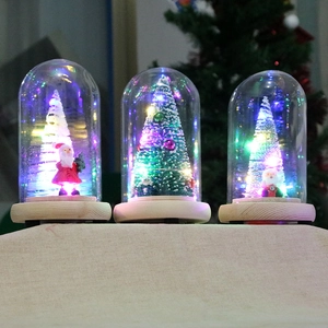 Three glowing mini Christmas trees in glass domes with wooden bases and LED lights