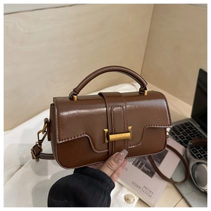 Macro shot of brown leather handbag featuring a gold buckle and vintage texture