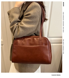 Close-up of retro brown leather tote bag worn with a grey wool coat in a minimalist setting