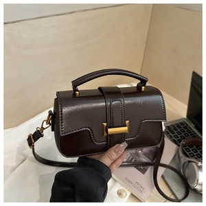 Brown leather crossbody bag on desk with laptop and lifestyle items for a modern look