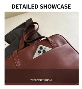 Detail of the front pocket on a vintage brown leather tote bag holding a large smartphone