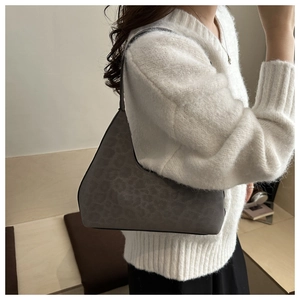 Detailed side view of a gray leopard print tote bag worn on shoulder by a model