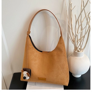 Gros plan sac hobo en daim jaune gingembre avec charmant pendentif chien en peluche