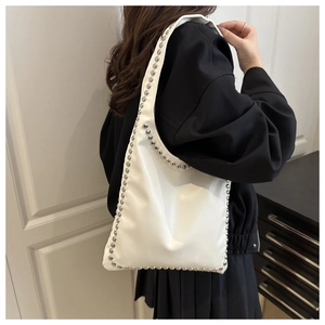 Detail of white PU leather bag featuring silver metallic studs on the curved shoulder strap