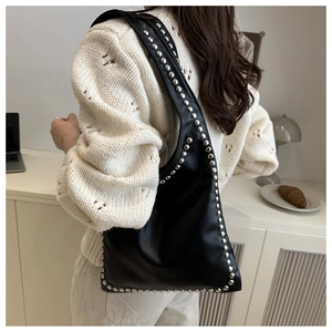 Detail of black faux leather hobo bag featuring silver rivets on a shoulder strap
