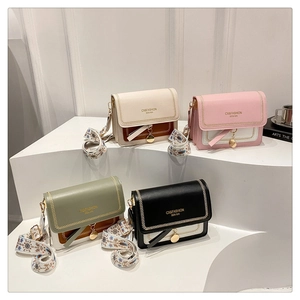 Detail of four color-block crossbody bags with embroidered wide straps on a white podium