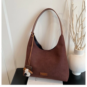 Détail du sac bandoulière en daim marron foncé avec charme chien en peluche et logo