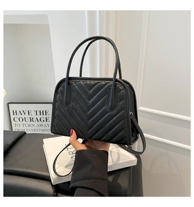 Detailed view of the black V-shaped quilted faux leather handbag with top handle