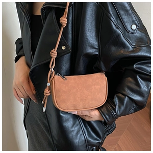 Gros plan d'un sac bandoulière marron avec bandoulière à nœuds porté par un mannequin