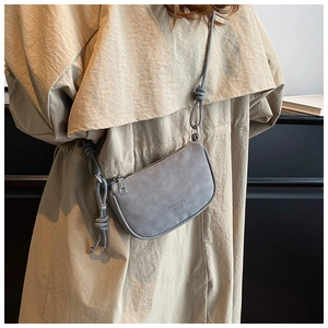 Détail du sac bandoulière gris en cuir mat avec pendentif M et bandoulière à nœud