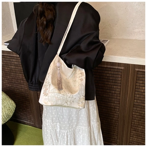 Détail d'un sac cabas jacquard de style chinois avec broderie bambou et pompon gris