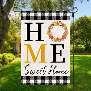 Close-up of Home Sweet Home garden flag with buffalo check borders in a green yard